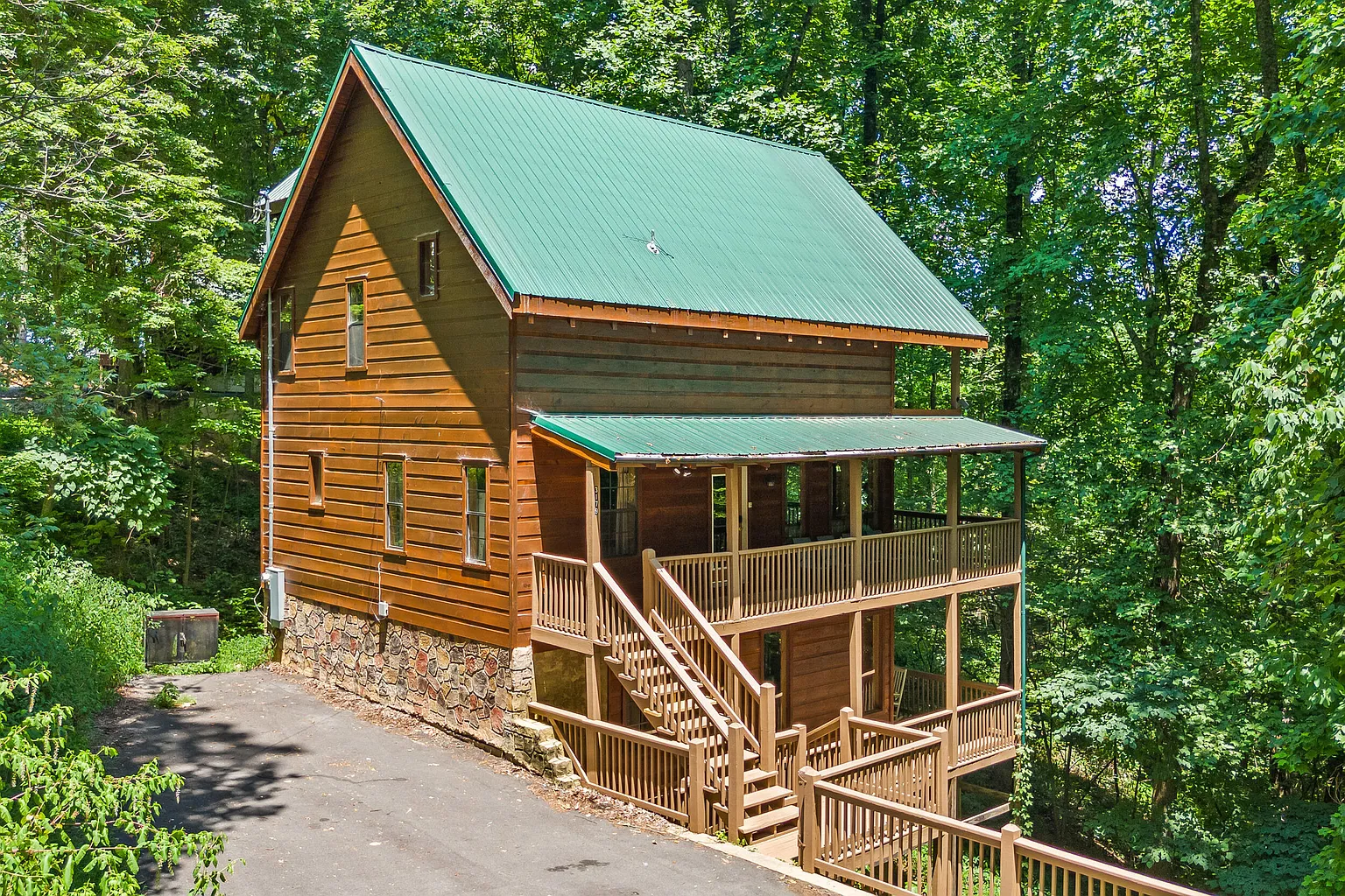 Smoky Summit Stays cabin exterior with green roof and wooded Shagbark setting in Sevierville, Tennessee