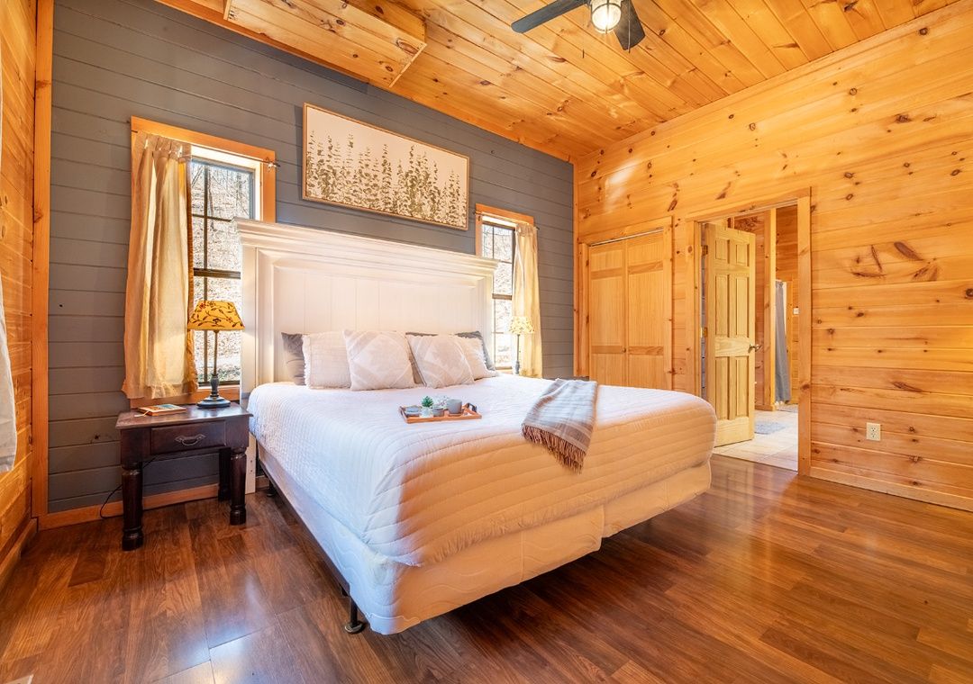 Bedroom with a made bed and warm wood walls