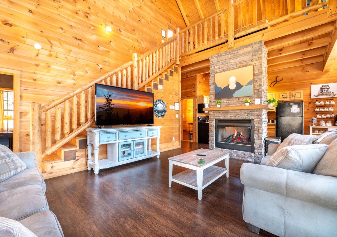 Lofted cabin living room with fireplace and staircase